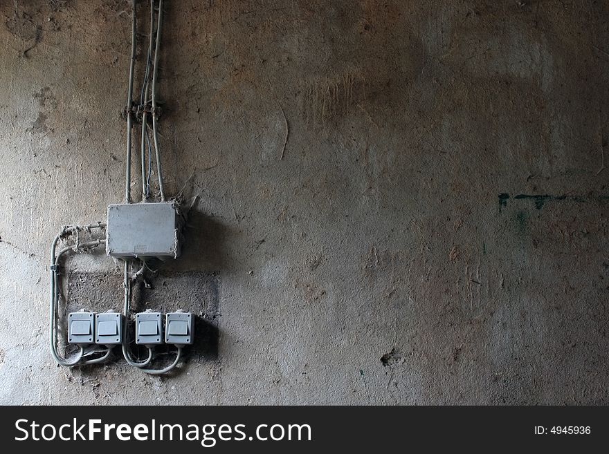 Old switches in an abandoned farm. The wall is filty and textured.