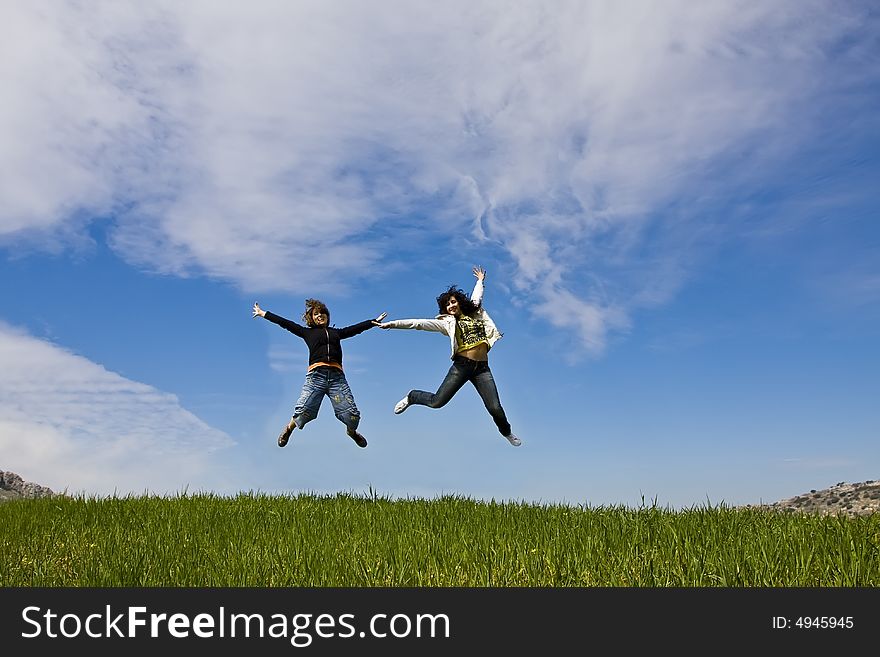 Young friends jumping on green meadow
