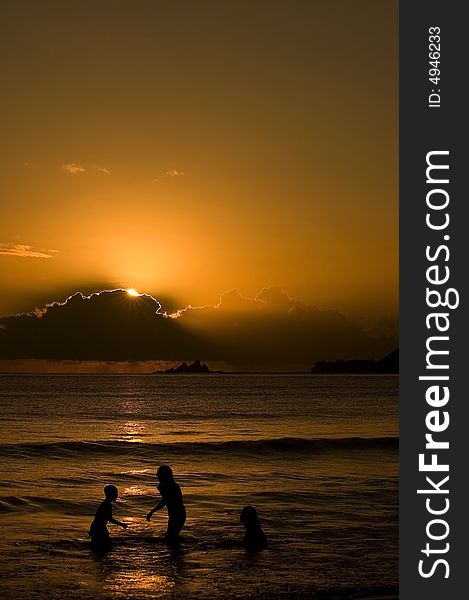 A morning sun coming up in the bay of Baler Aurora with three kids enjoying the water.