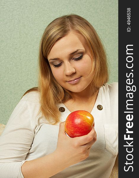 The nice girl lovely looks at a red apple. The nice girl lovely looks at a red apple