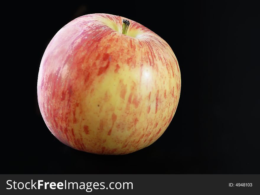 Close up of a red and yellow apple on a black background