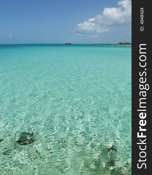 Caribbean bay with clear water, blue sky clouds and island.