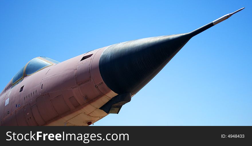 An F-105D Thunderchief fighter aircraft stands out dramatically against a clear blue sky