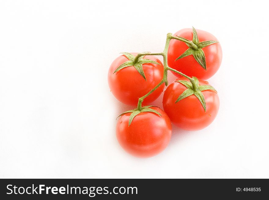 Four small red tomatoes on green brunch isolated. Four small red tomatoes on green brunch isolated