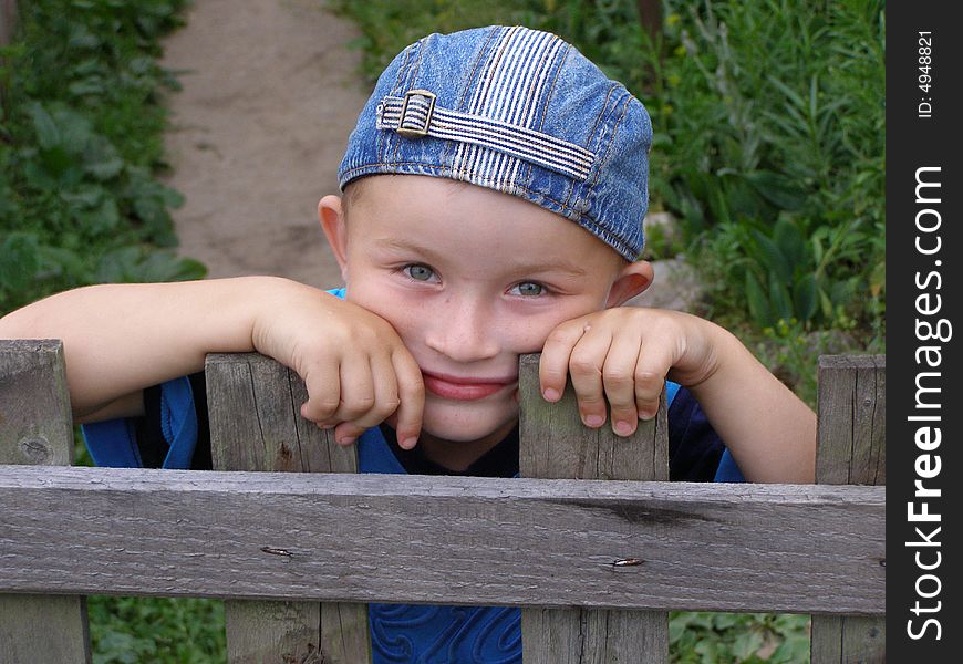 Little Boy Leaned Against The Fence