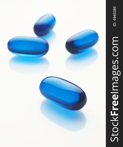 Blue capsules on white background, vertical image
