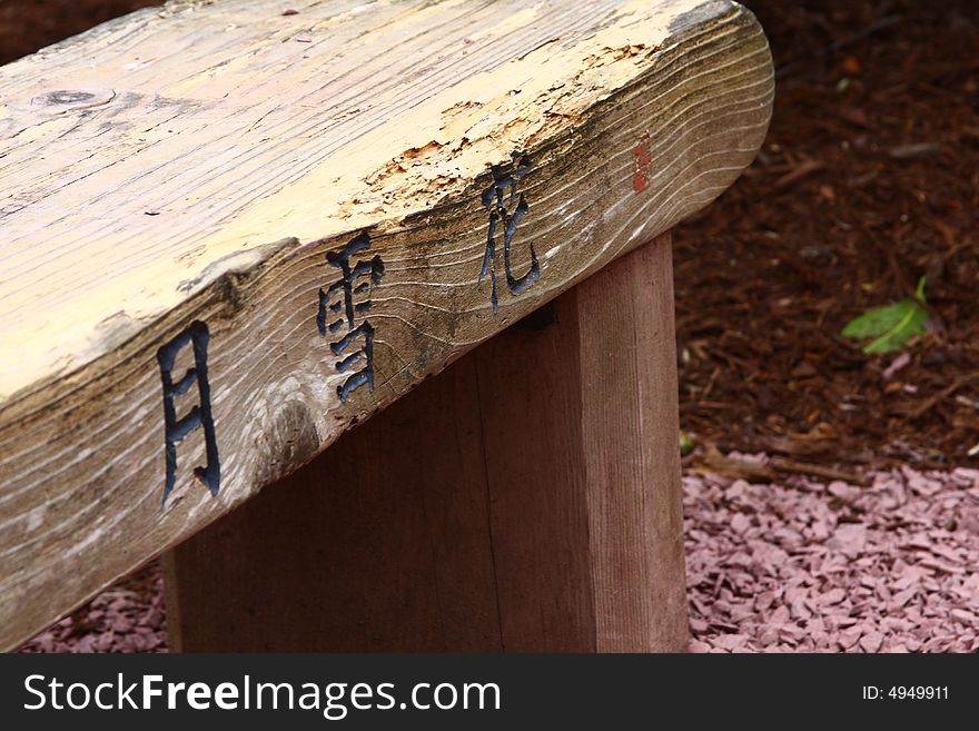 Wooden bench in a garden with Japanese inscriptions. Wooden bench in a garden with Japanese inscriptions.