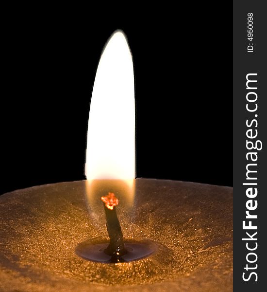 A close up of a burning candle over a black background. A close up of a burning candle over a black background.