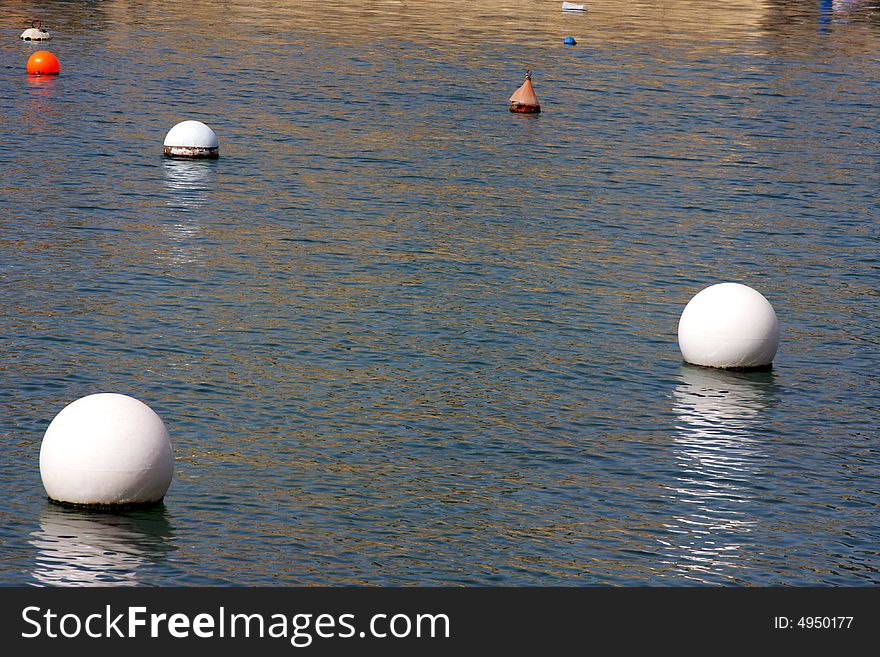 Several bouys floating in a gentle ocean.
