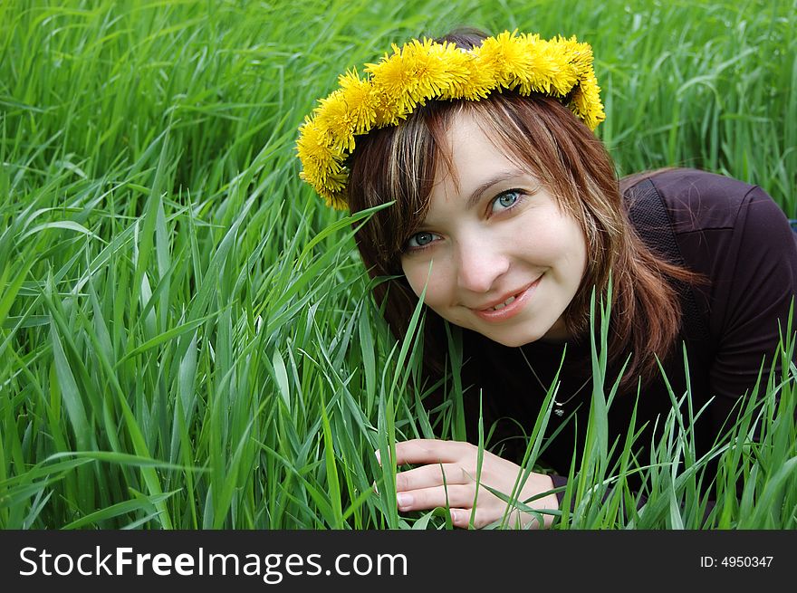 Girl with dandelion diadem in hair over green grass. Girl with dandelion diadem in hair over green grass