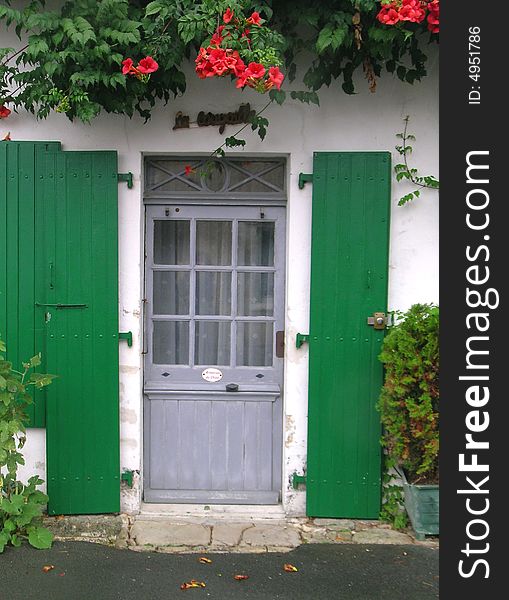 Grey wooden door with green shutters