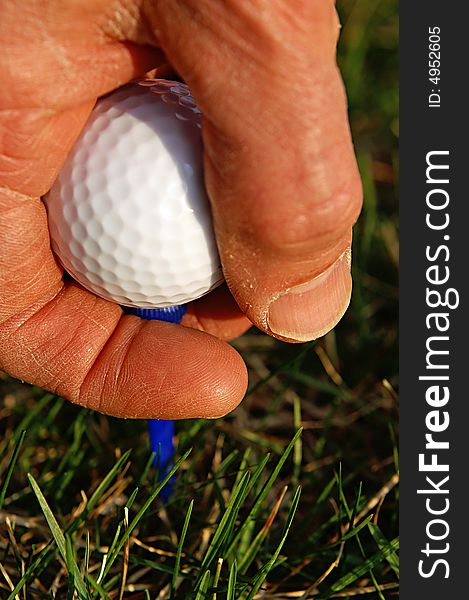 Anticipating the perfect drive as golfer puts his ball and tee in place. Anticipating the perfect drive as golfer puts his ball and tee in place