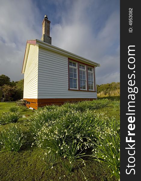 Historic school house with white flowers in foreground, South Coast, New Zealand