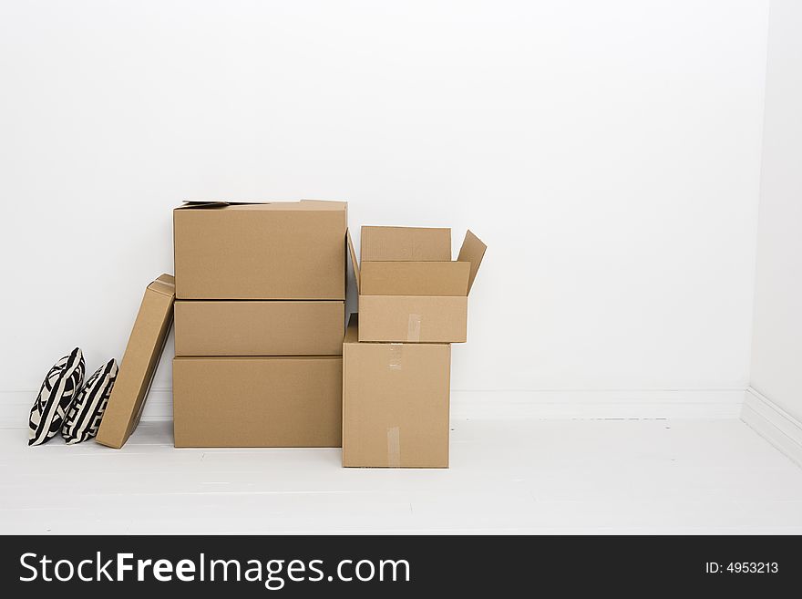 Empty white room with several moving boxes. One box is open. Empty white room with several moving boxes. One box is open.