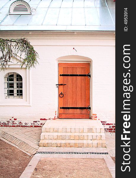 White small house with a wooden door.