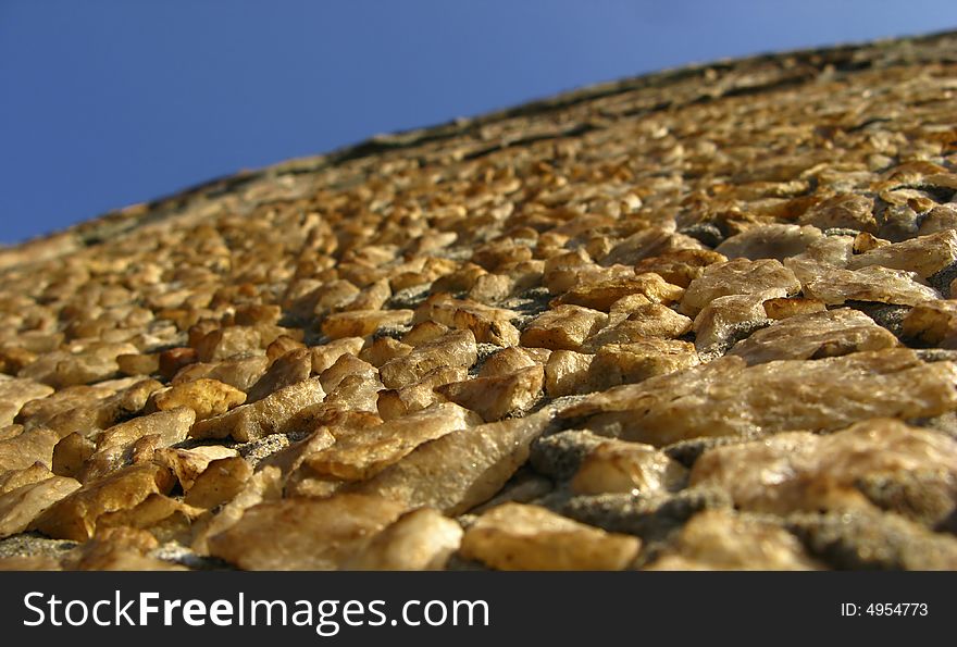 Fragment of wall, surface laid out from stones on blue sky background