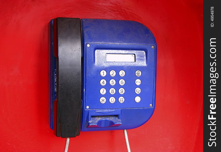 Public telephone on red background, close up