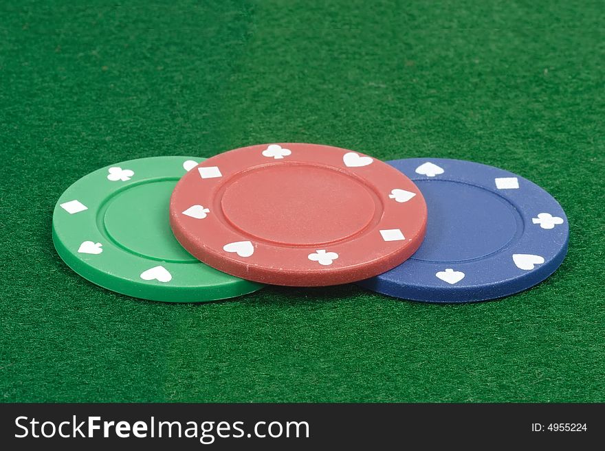 Three Poker chips on green background. Three Poker chips on green background