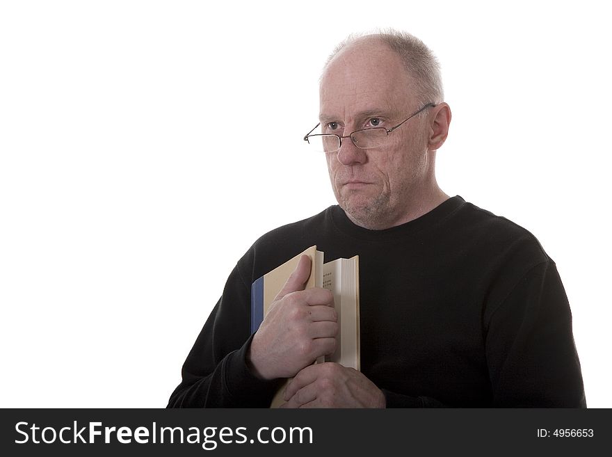 An older guy in a black shirt and glasses holding a book with a thoughtful expression. An older guy in a black shirt and glasses holding a book with a thoughtful expression