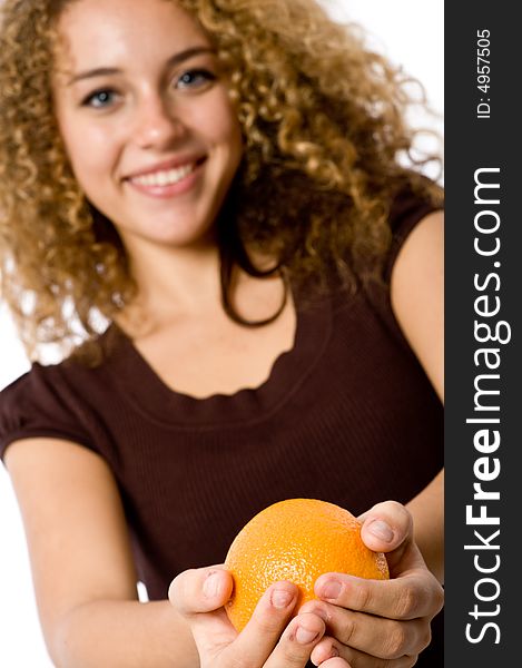 A pretty smiling young woman holding an orange (focus on orange). A pretty smiling young woman holding an orange (focus on orange)