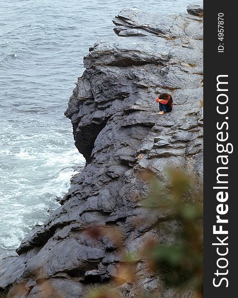 A girl is sad and lonely sitting on the rocks. A girl is sad and lonely sitting on the rocks