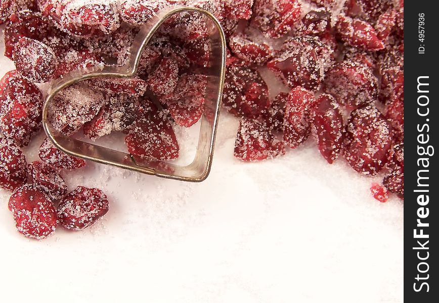 Image of dried cranberries mixed with white granulated sugar, with a small heart-shaped cookie cutter resting upon the edge of the mixture. Image of dried cranberries mixed with white granulated sugar, with a small heart-shaped cookie cutter resting upon the edge of the mixture.