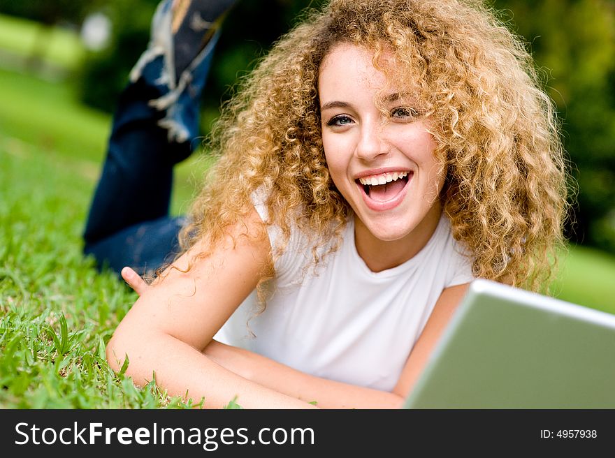 A young woman lying on the grass with laptop computer. A young woman lying on the grass with laptop computer