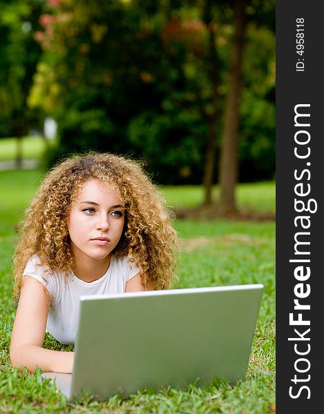 A young attractive woman using laptop in the park. A young attractive woman using laptop in the park