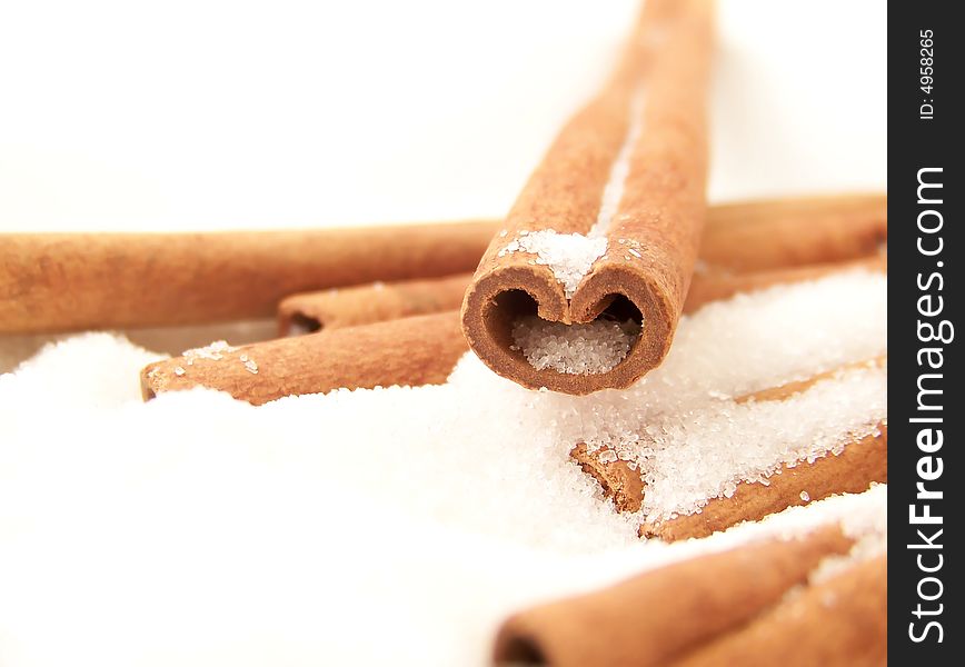 Horizontal image of a heart-shaped cinnamon stick in white granulated sugar, with other sticks visible. Horizontal image of a heart-shaped cinnamon stick in white granulated sugar, with other sticks visible.