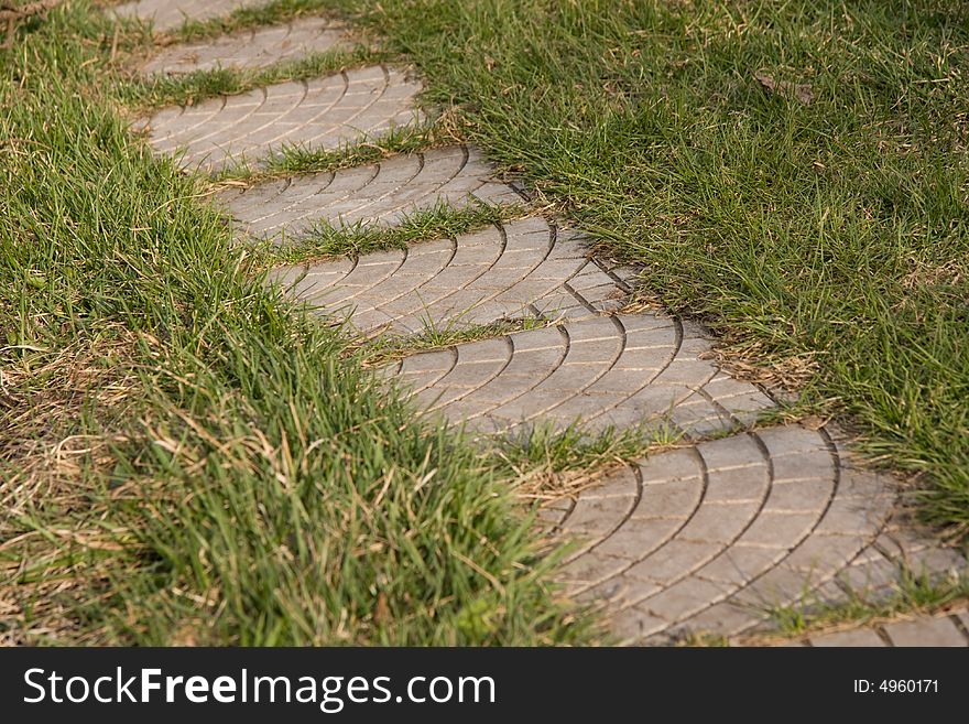 Path in garden consist of separated slabs surrounded with last year and spring grass. Path in garden consist of separated slabs surrounded with last year and spring grass