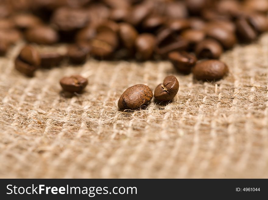 Freshly roasted coffee beans on sackcloth with copyspace. Shallow depth of field. Focus on center of image