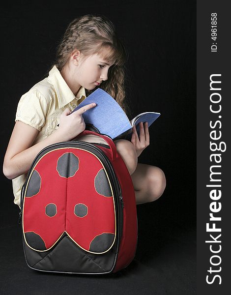 Girl with bag, looking to notebook on black background