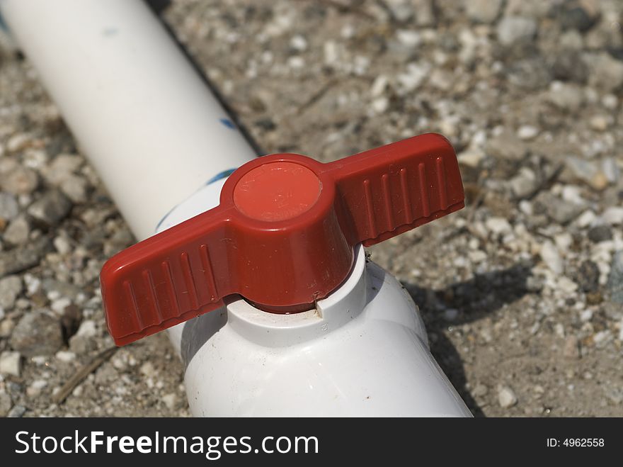 Red valve on PVC irrigation pipe in closed position