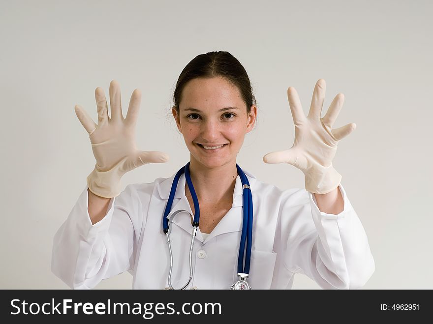 Young female doctor holding her gloved hands out and smiling playfully