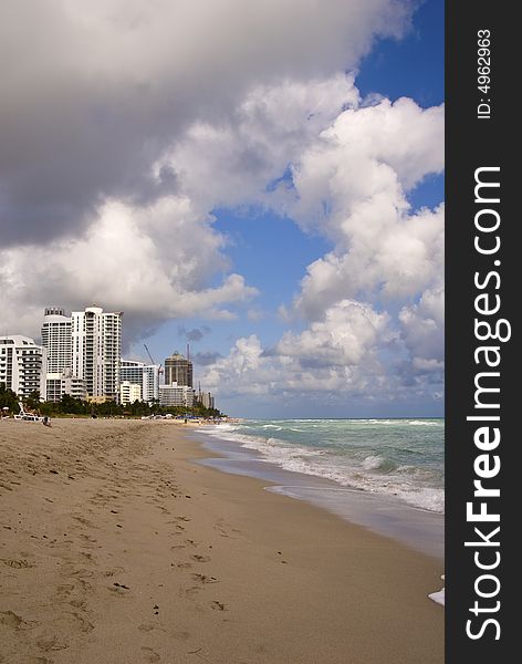 Beach with cloudy sky and tall buildings in distance in miami florida