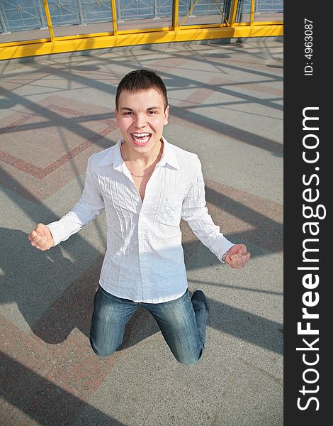 Young man stands on knees on the footbridge