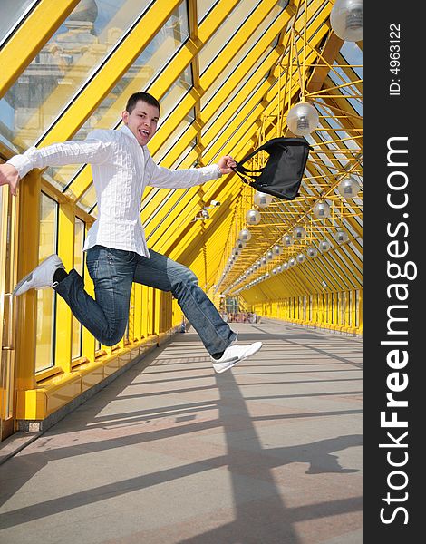 Young man jumps with bag on footbridge