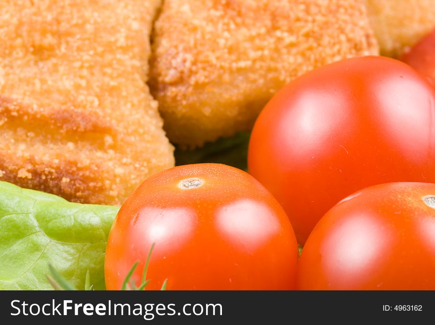 Appetizing fried chicken nuggets  with tomatoes, cucumber and pepper on salad leaves. Close-up. Selective focus. Appetizing fried chicken nuggets  with tomatoes, cucumber and pepper on salad leaves. Close-up. Selective focus.