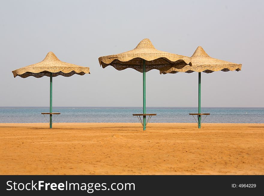 Beach on the coast of the Red Sea. Three single beach umbrella. Morning. (12,8 MP FullFrame). Beach on the coast of the Red Sea. Three single beach umbrella. Morning. (12,8 MP FullFrame)