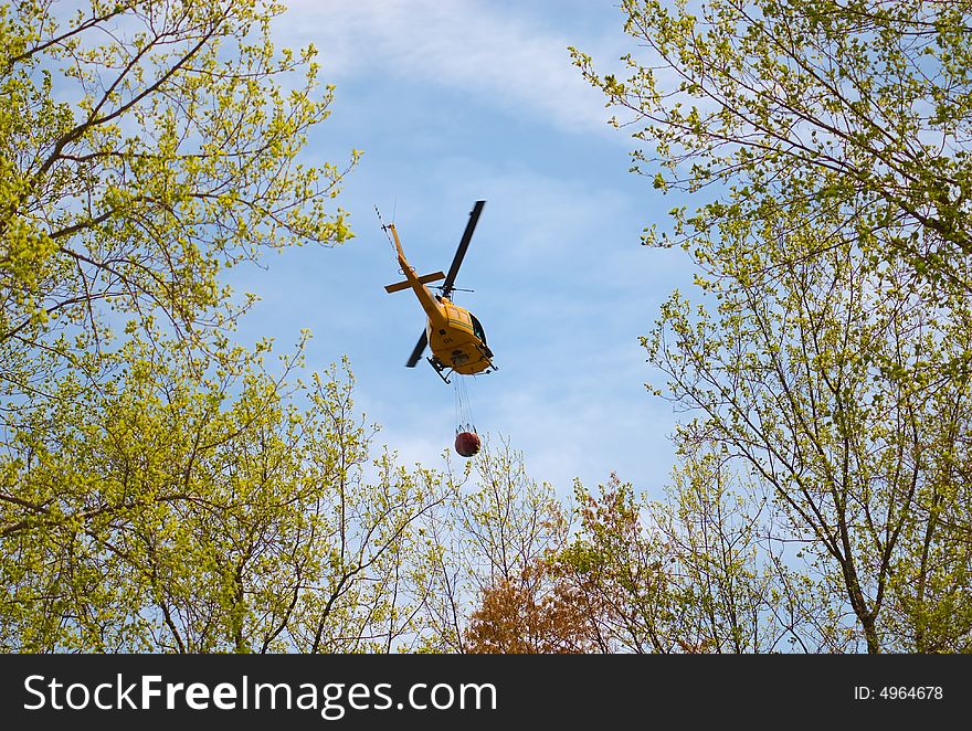 A rescue helicopter carrying water to a forest fire.