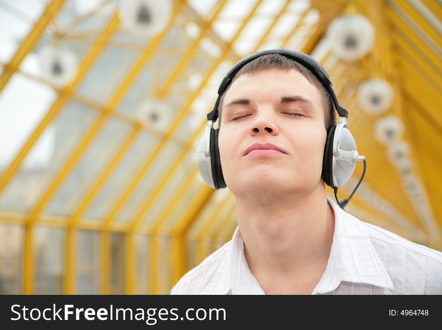 Young man listens music on footbridge