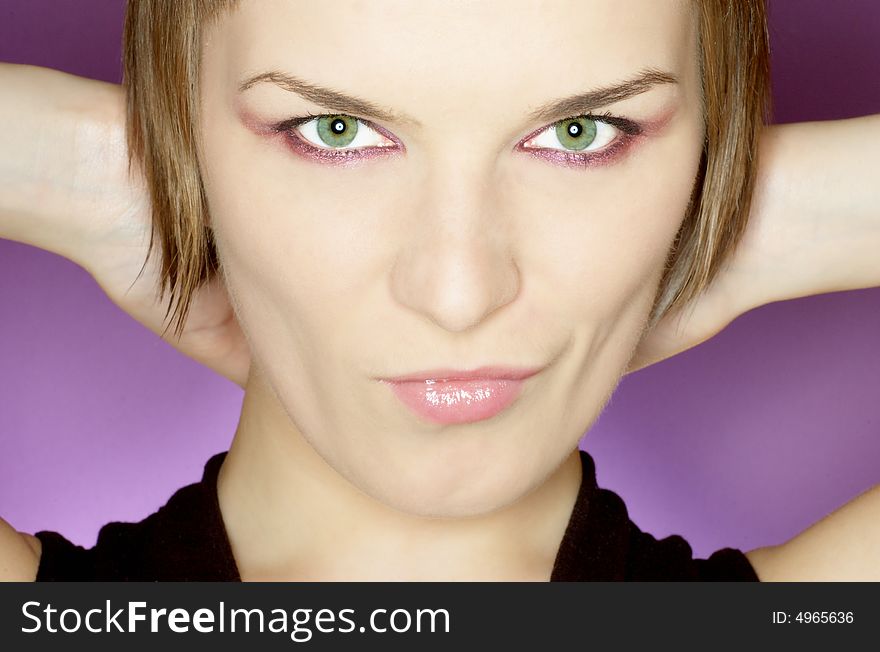 Beautiful woman with green eyes on purple background, hands on her neck, close up