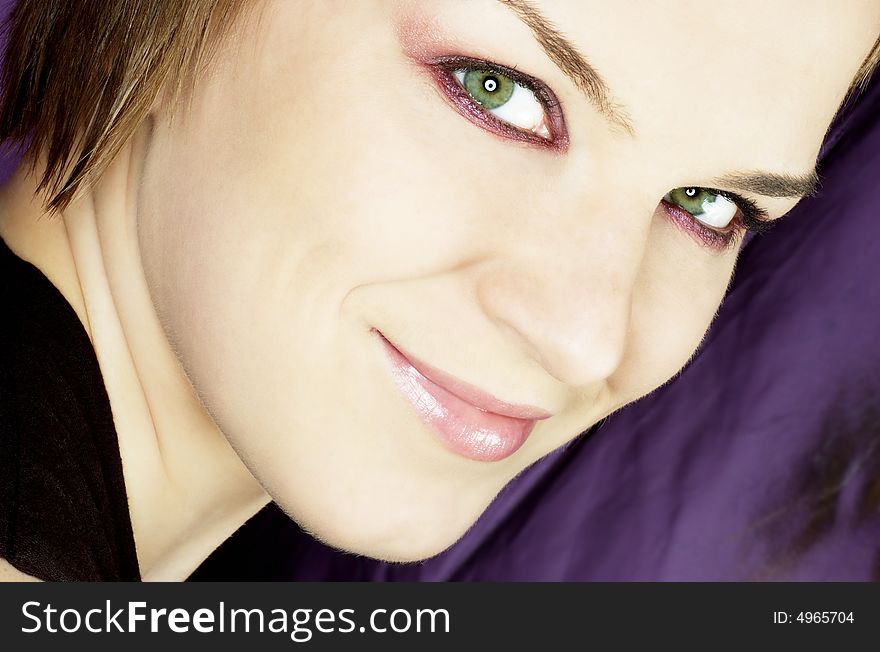 Beautiful woman with green eyes on purple background, close up