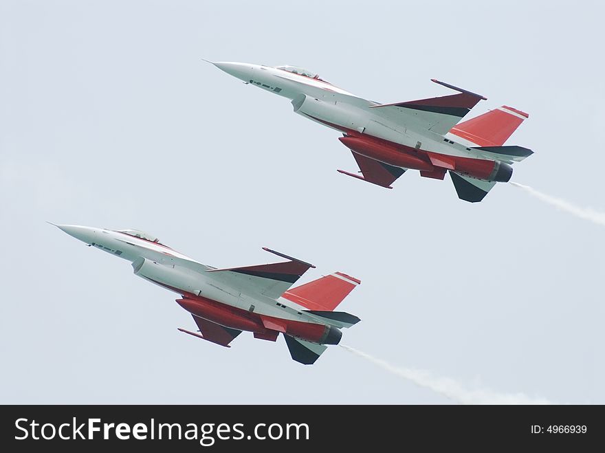 Two white and red F-16 fighter airplanes flying in formation. Two white and red F-16 fighter airplanes flying in formation