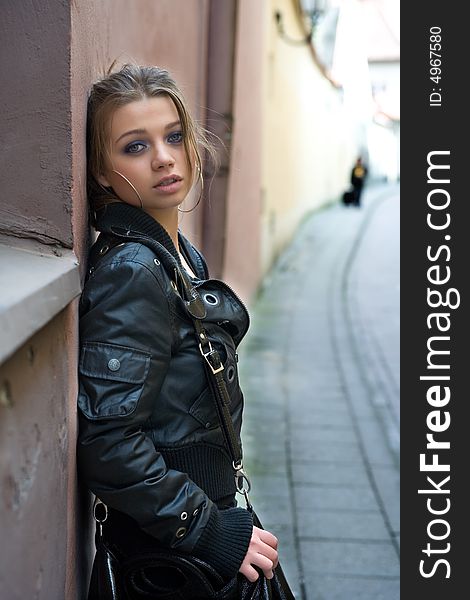 Portrait of the girl near wall in an old town