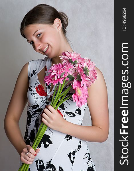 Nice girl in a dress with flowers on a grey background