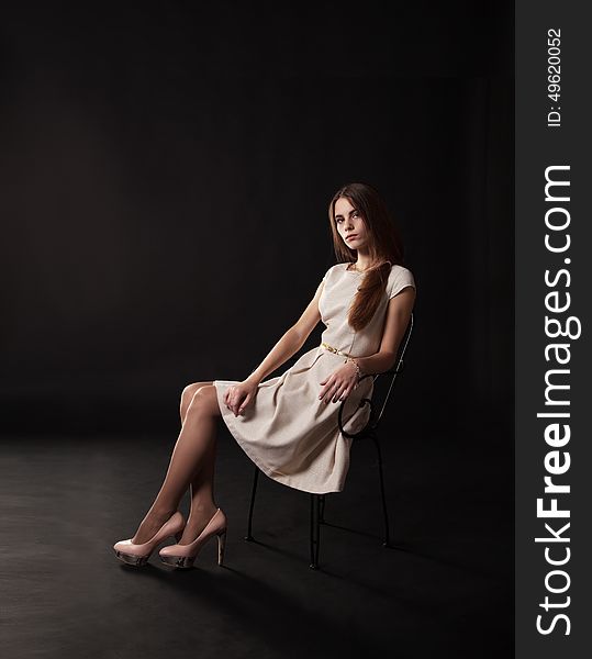 Young beautiful girl in a bright dress sitting on the chair