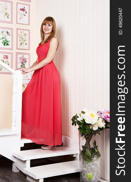 Young beautiful woman in red dress standing on the stairs. Young beautiful woman in red dress standing on the stairs