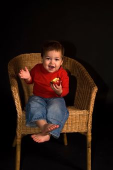 Boy Sitiing In Armchair, Eating Apple And Shouting Stock Image