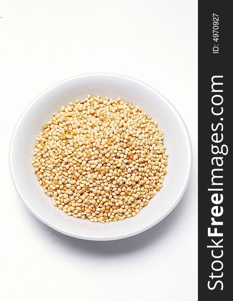 Millet seeds in bowl aginst white background